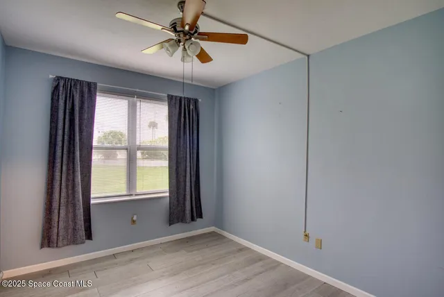 an empty room with windows and fan