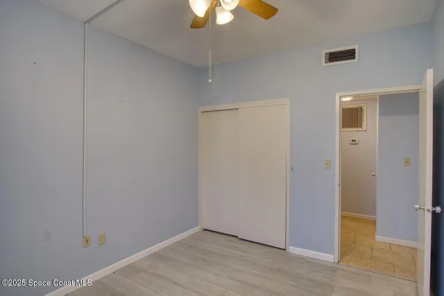 a view of an empty room with wooden floor and a chandelier fan