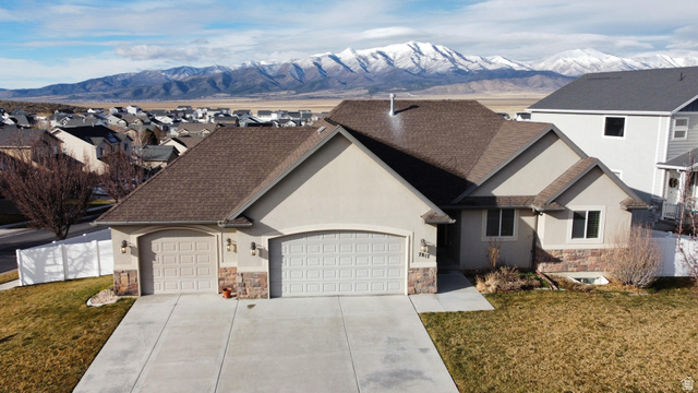 7817 North Blue Spruce Road Eagle Mountain, UT 84005 - Photo 1 of 1 View of front of property with stone siding, stucco siding, a garage, concrete driveway, and a shingled roof
