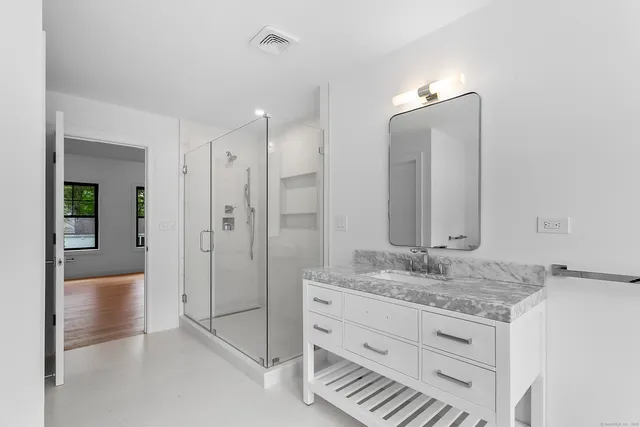a bathroom with a granite countertop sink two mirror and shower