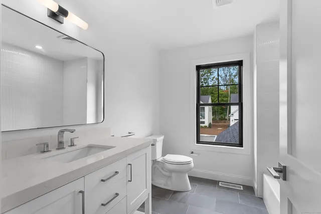 a bathroom with a granite countertop sink a toilet and a window