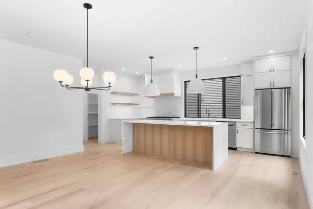 a kitchen with stainless steel appliances granite countertop a sink a refrigerator and a wooden floor