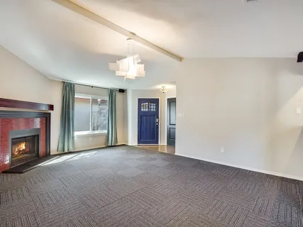a view of an empty room with window and fire place