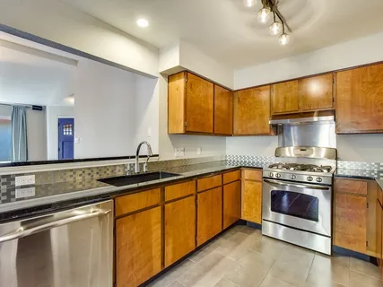 a kitchen with stainless steel appliances granite countertop a sink a stove and a wooden floors