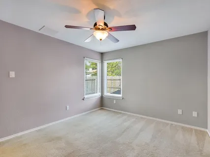 an empty room with a window and a fan