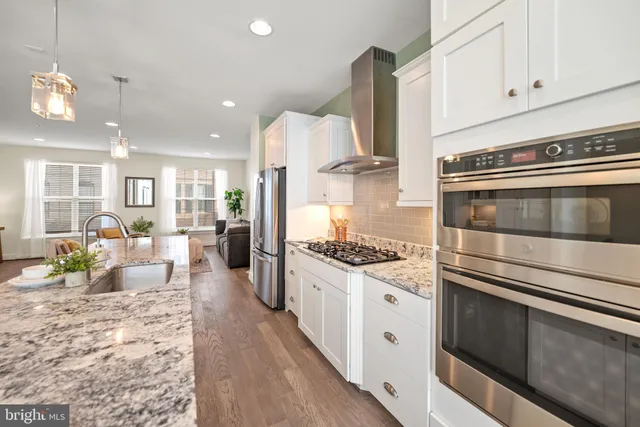 a kitchen with stainless steel appliances kitchen island granite countertop a stove and white cabinets
