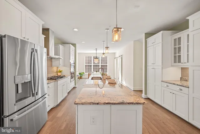 a kitchen with stainless steel appliances granite countertop a refrigerator a oven and a sink with wooden floor