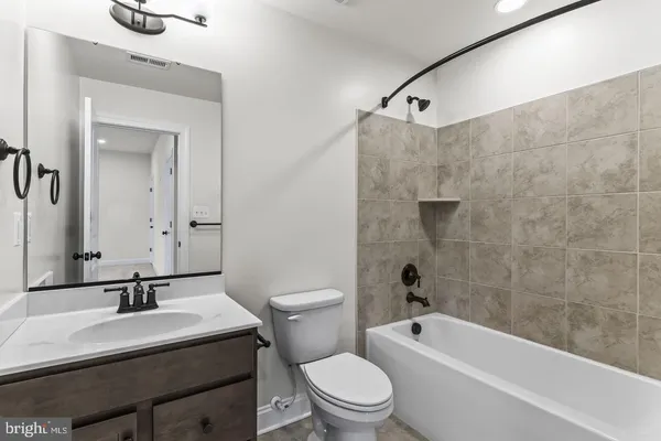 a bathroom with a granite countertop sink a toilet a mirror and shower