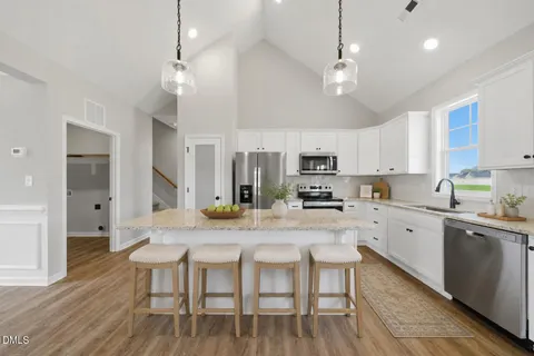 a kitchen with stainless steel appliances a table chairs refrigerator and cabinets