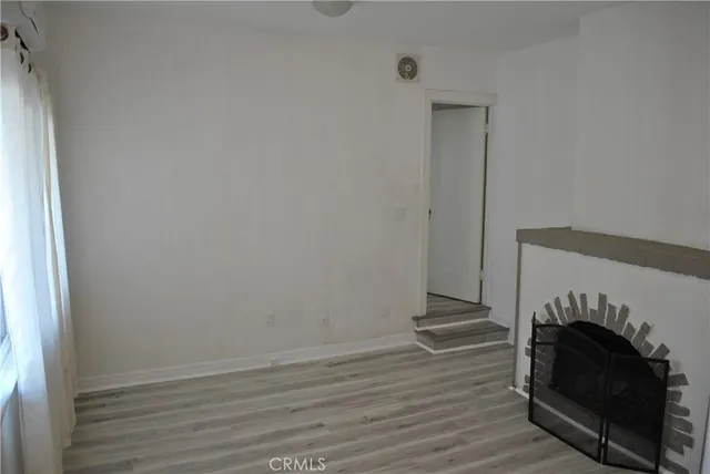 a view of a livingroom with wooden floor and a fireplace