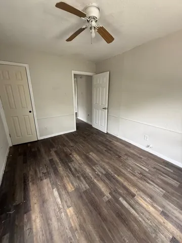 a view of an empty room with wooden floor ceiling fan