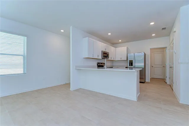 a kitchen with white cabinets and refrigerator
