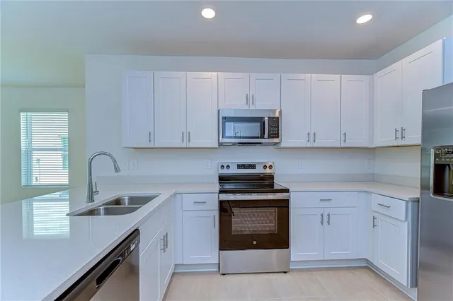 a kitchen with cabinets appliances a sink and a window