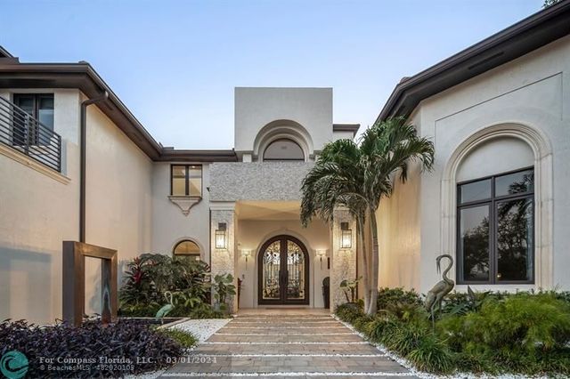 a view of a house with large windows and plants
