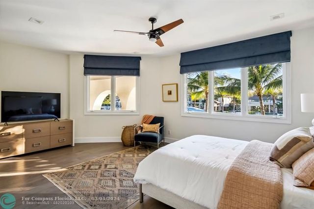 a bedroom with a bed a flat screen tv and windows