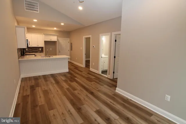 a view of kitchen with stainless steel appliances wooden floor and cabinets