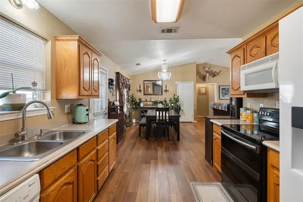 a kitchen with stainless steel appliances granite countertop a stove top oven a sink a dining table and chairs with wooden floor