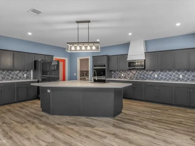 a large kitchen with kitchen island a counter space a sink stainless steel appliances and cabinets