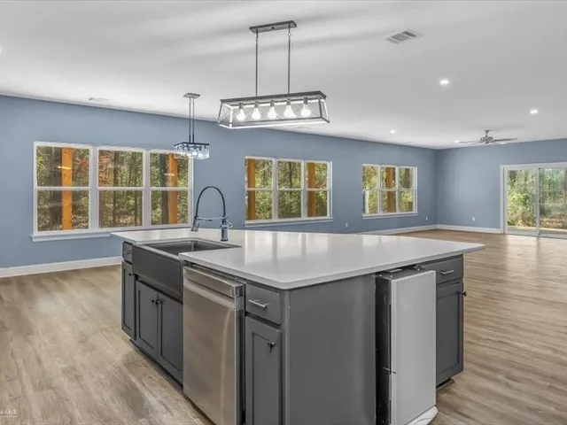 a kitchen with stainless steel appliances granite countertop a sink a window and wooden floor