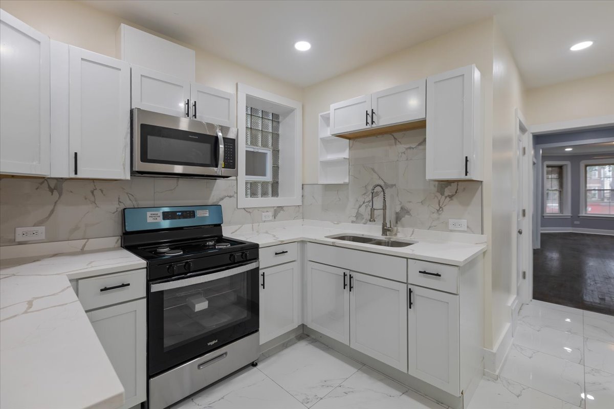4626 West Monroe Street Chicago, IL 60644 - Photo 23 of 34 a kitchen with stainless steel appliances granite countertop a sink dishwasher a stove and a refrigerator with wooden cabinets