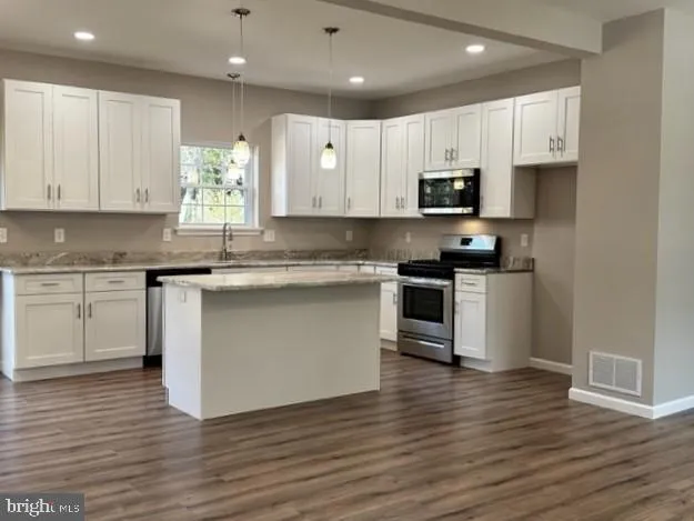 a kitchen with granite countertop a sink stainless steel appliances and cabinets
