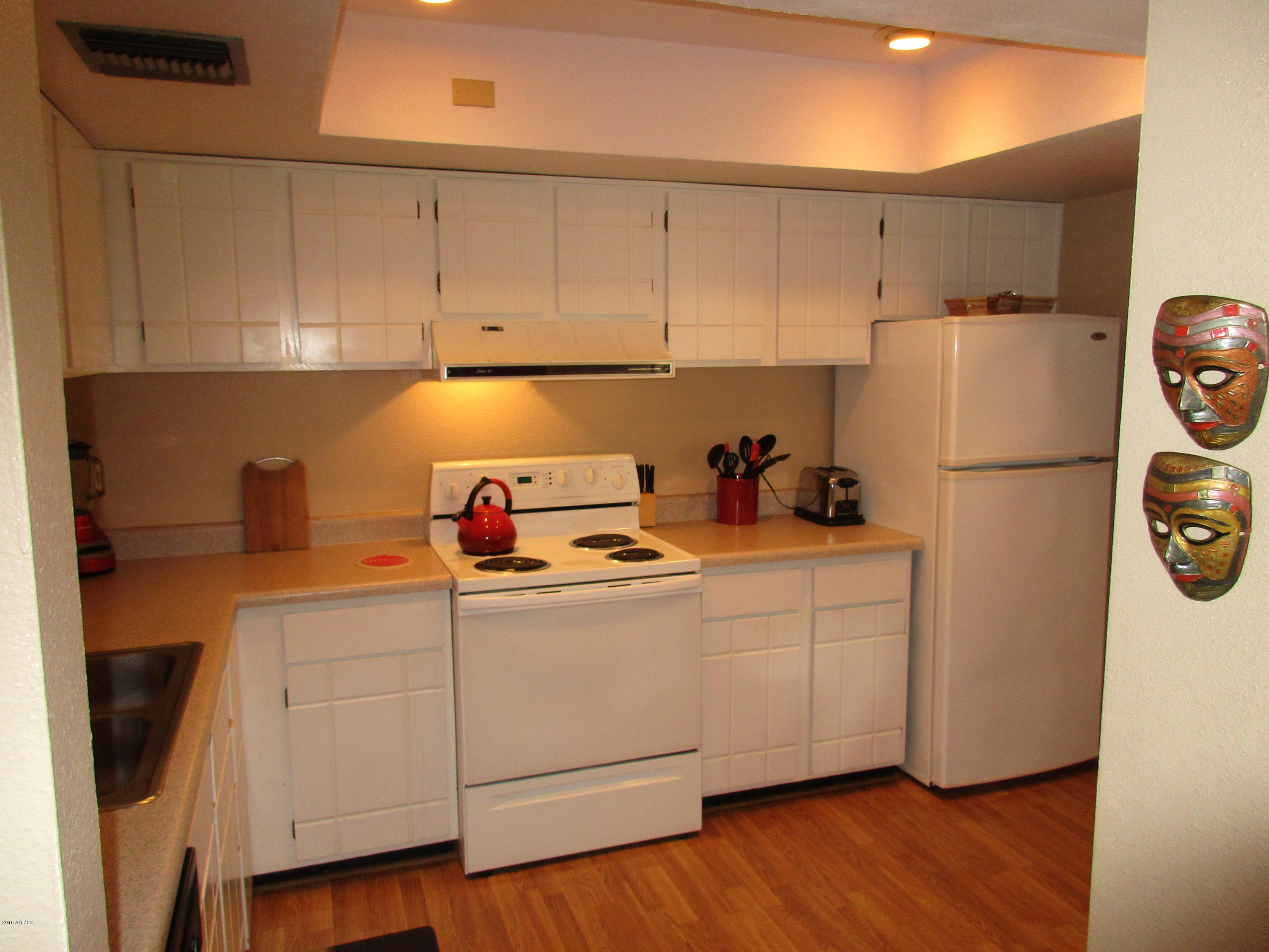 4201 East Camelback Road, Unit 22 Phoenix, AZ 85018 - Photo 9 of 23 a kitchen with refrigerator a stove a sink and cabinets