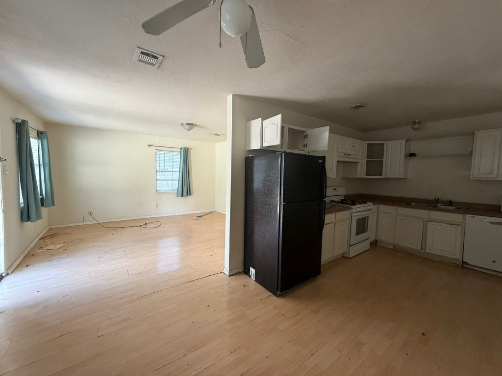 1300 Delano Street Austin, TX 78721 - Photo 4 of 11 Kitchen with white appliances, white cabinets, open shelves, light wood-style floors, and a textured ceiling