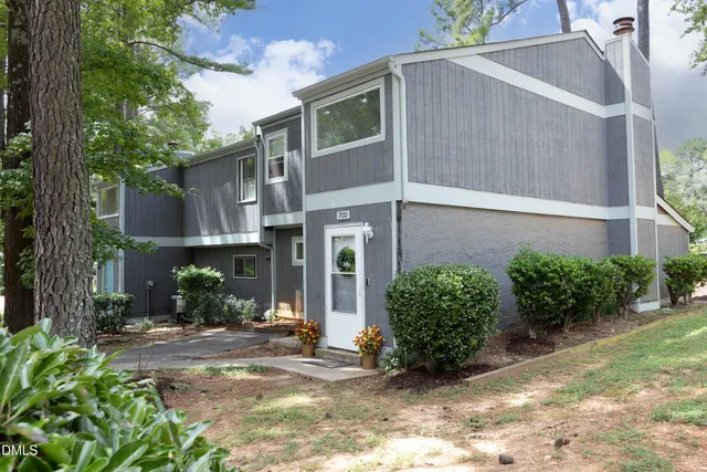 a view of a house with brick walls plants and large tree