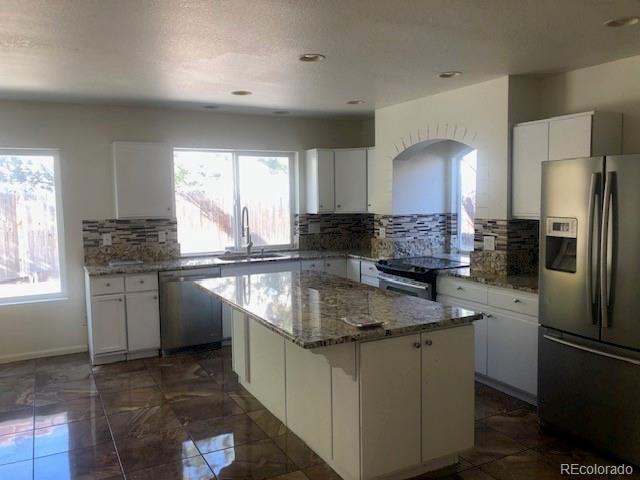Undisclosed Address Commerce City, CO 80022 - Photo 8 of 12 a kitchen with stainless steel appliances granite countertop a sink a stove a refrigerator a center island and a window