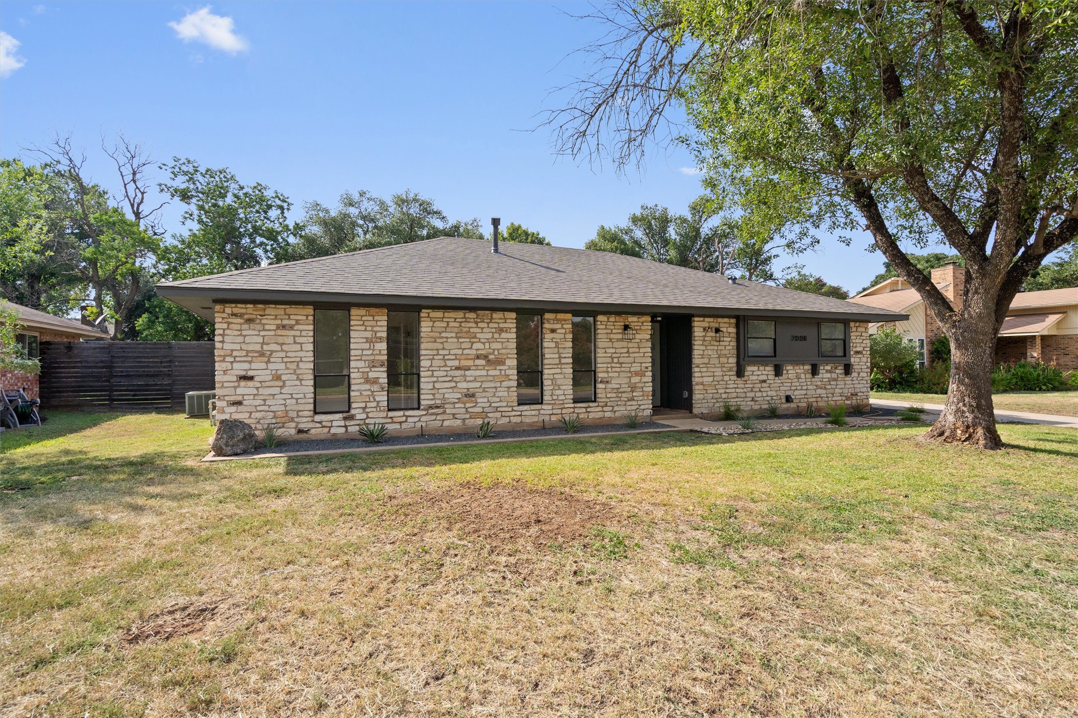 Ranch-style house featuring stone siding and roof with shingles