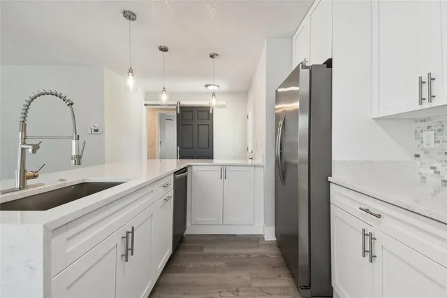 a kitchen with granite countertop a sink and refrigerator