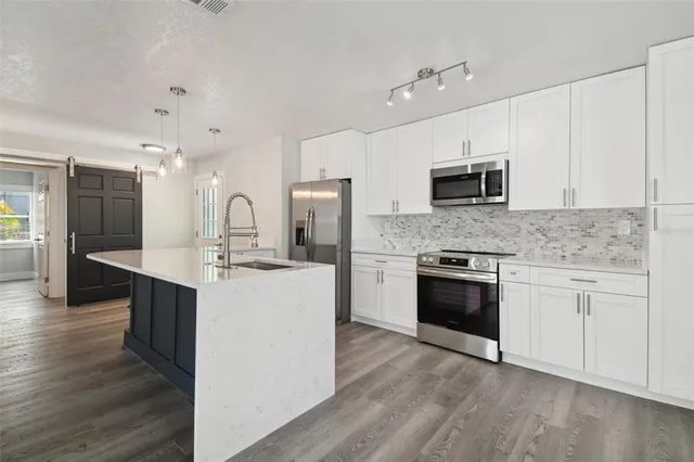 a large kitchen with cabinets wooden floor and stainless steel appliances