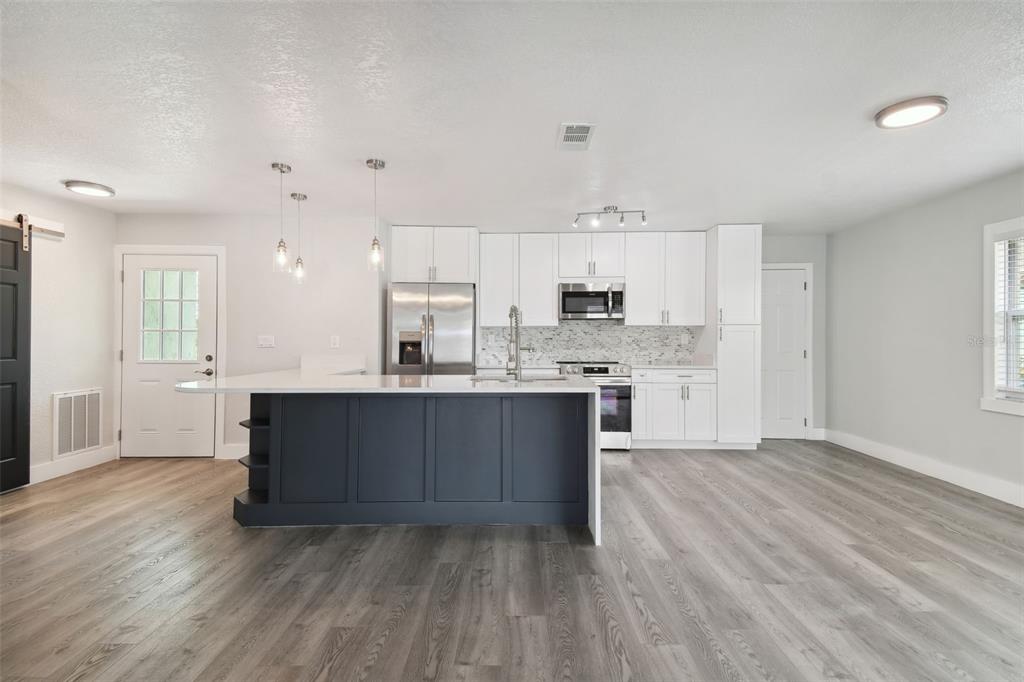 4482 Kingston Drive Hernando Beach, FL 34607 - Photo 22 of 49 a large kitchen with kitchen island a sink dishwasher a stove and a refrigerator with wooden floor