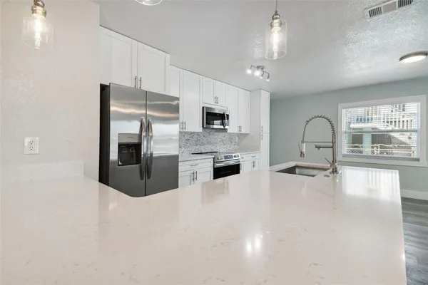 a large kitchen with granite countertop a large counter top stainless steel appliances and a window