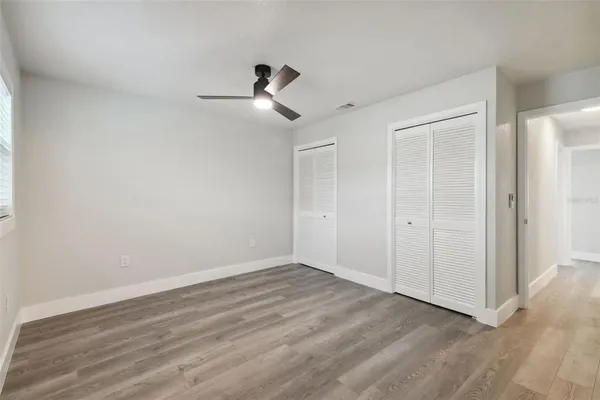 a view of empty room with wooden floor and ceiling fan