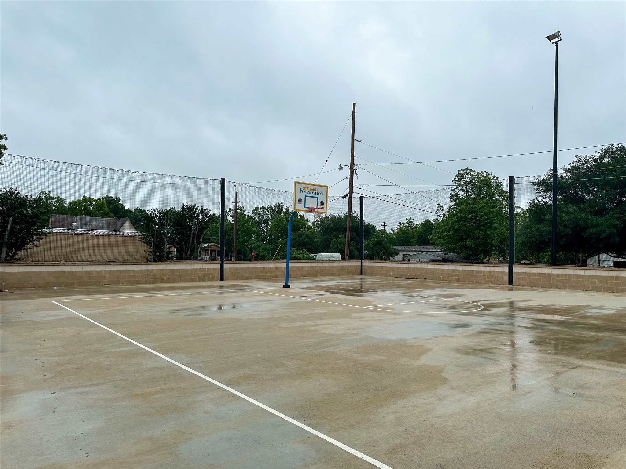 608 Lamar Street Luling, TX 78648 - Photo 6 of 7 Concrete sport court featuring painted white lines, an adjustable height basketball hoop, and perimeter netting