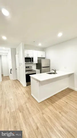 a large white kitchen with kitchen island a sink stainless steel appliances and cabinets