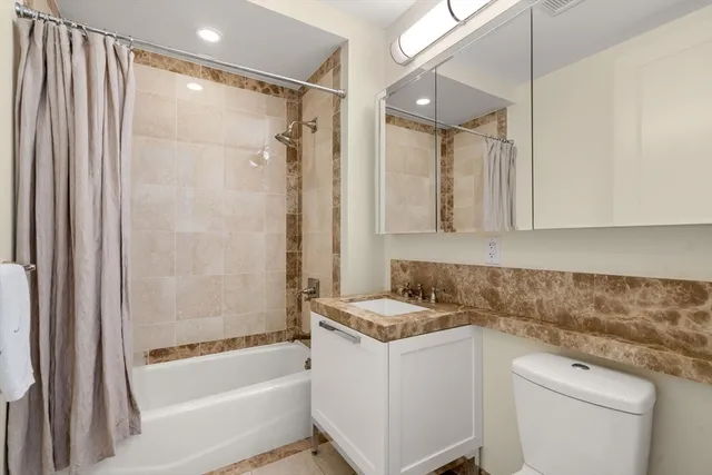 a bathroom with a granite countertop sink a toilet and shower