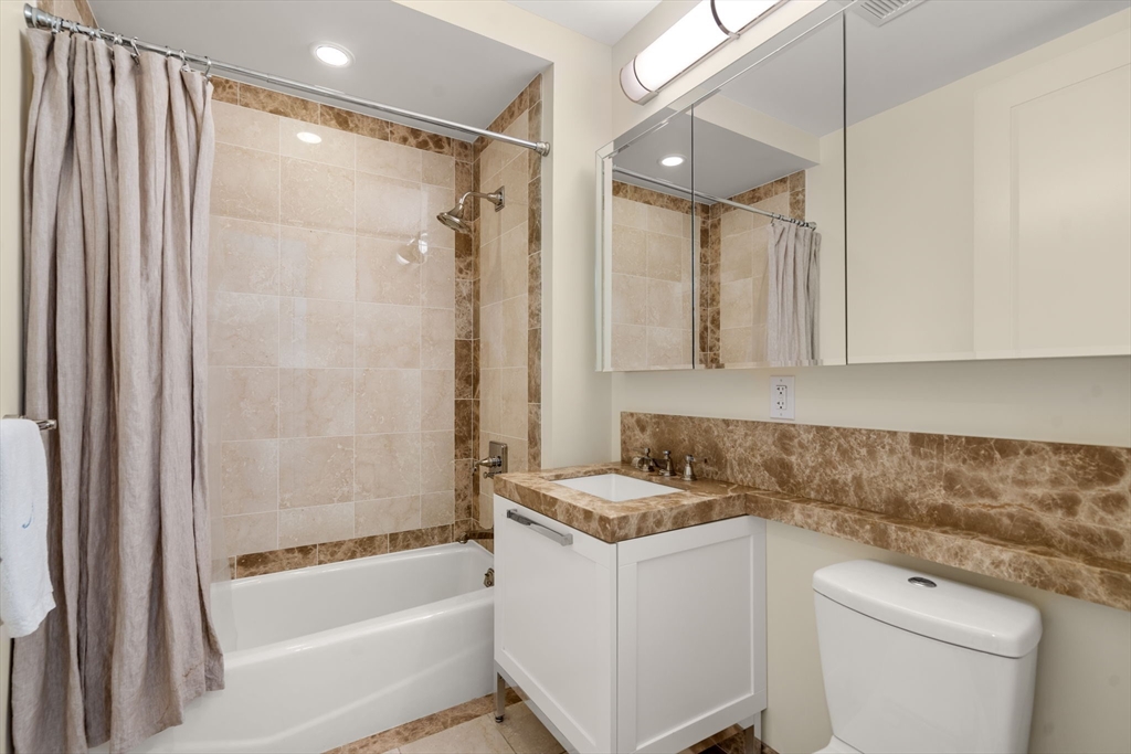 400 Stuart Street, Unit 15J Boston, MA 02116 - Photo 9 of 12 a bathroom with a granite countertop sink a toilet and shower