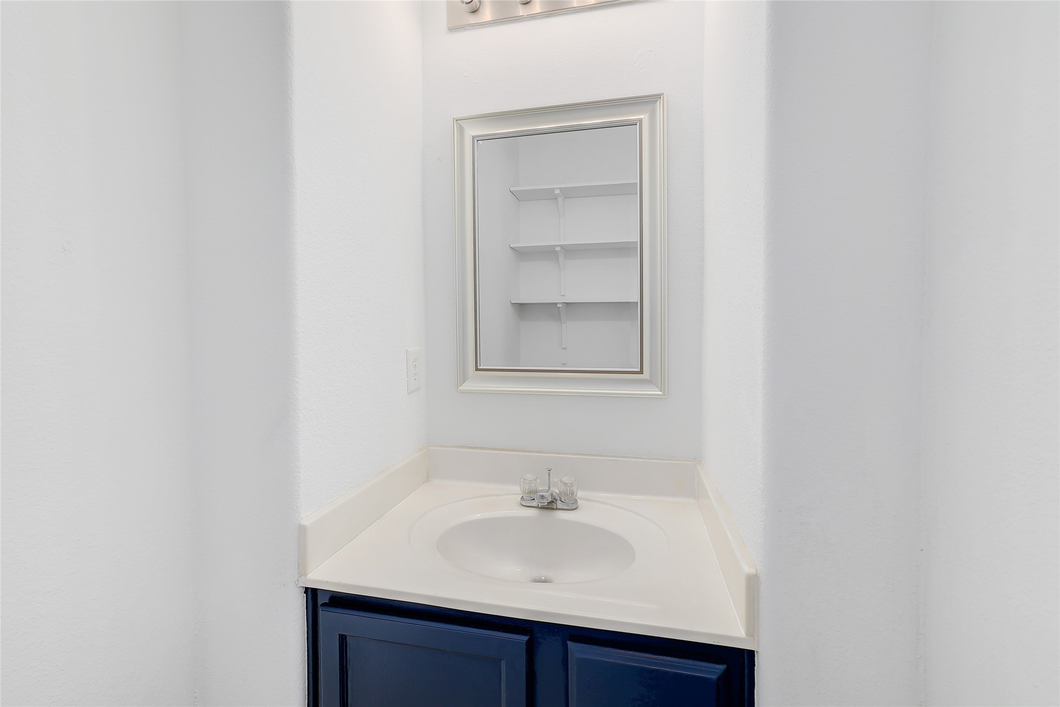 203 Ran Road Leander, TX 78641 - Photo 27 of 31 Down stairs half-bath features vanity area features a framed mirror set within a recessed wall alcove.