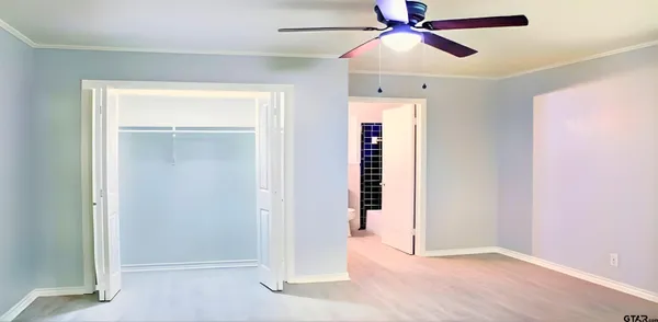 an empty room with closet and a chandelier fan
