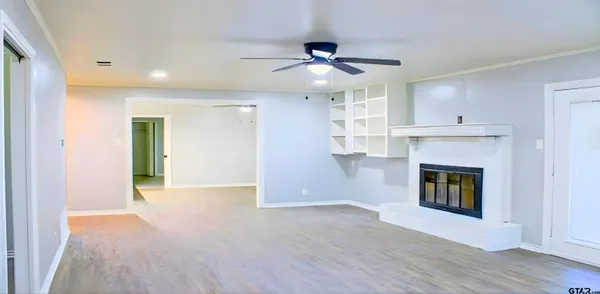a view of an empty room with wooden floor and a fireplace