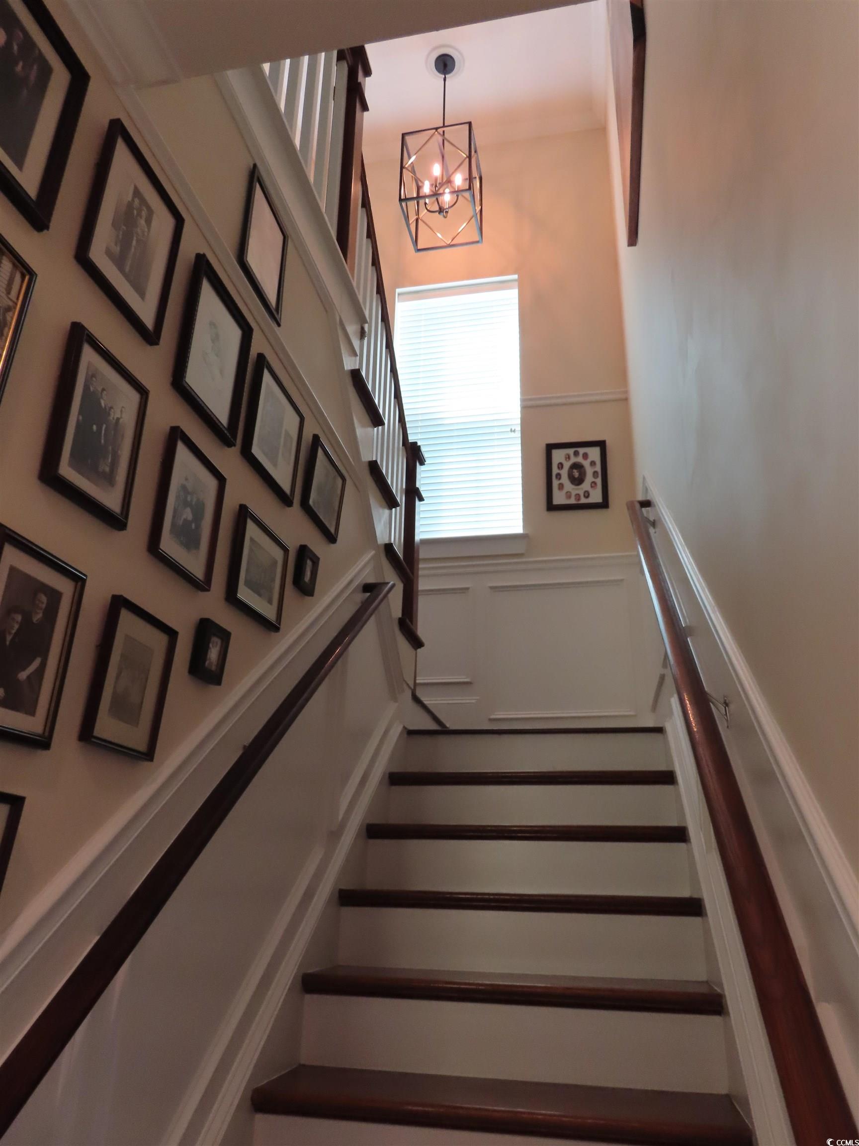 800 Curtis Brown Lane Myrtle Beach, SC 29577 - Photo 19 of 40 Staircase with wainscoting, a decorative wall, and a chandelier