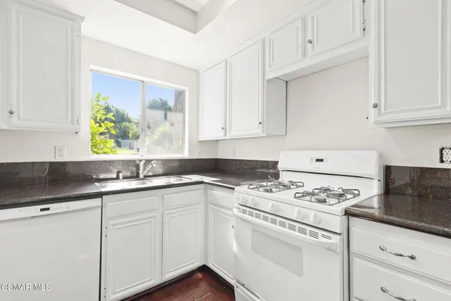 a kitchen with granite countertop a stove sink and cabinets
