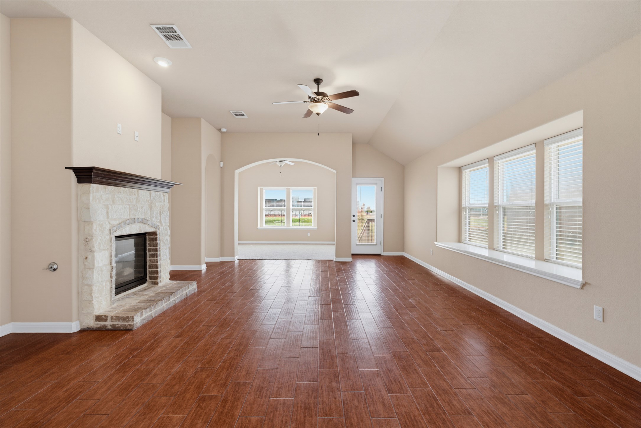 6033 Roma Street Round Rock, TX 78665 - Photo 8 of 28 Rich wood-look flooring and a stone fireplace anchor this airy, open living space.
