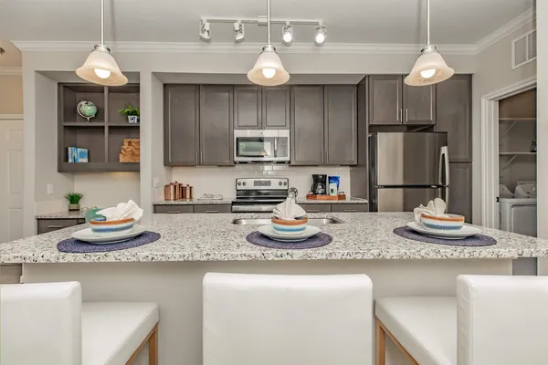 a kitchen with a sink a microwave a refrigerator and chairs