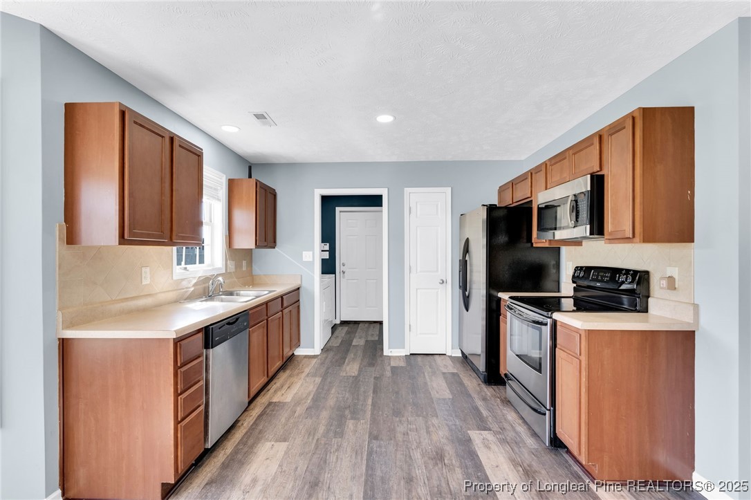 229 Cape Fear Road Raeford, NC 28376 - Photo 18 of 46 a kitchen with stainless steel appliances granite countertop a refrigerator a stove top oven a sink dishwasher and wooden cabinets with wooden floor