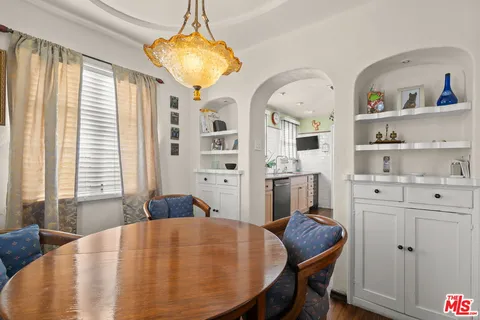 a kitchen with stainless steel appliances granite countertop a sink a stove top oven a chimney cabinets and a window