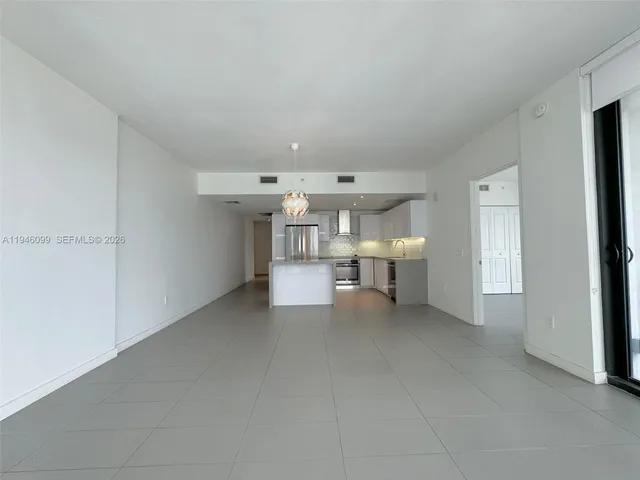 a view of empty room with kitchen and window