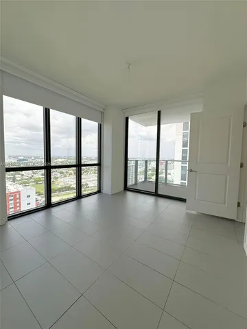 a view of an empty room with windows and chandelier